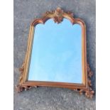 A reproduction carved mirror, the moulded frame surmounted by foliate scroll carved crest, with
