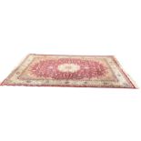 A Wilton rug woven in the oriental palette with central floral medallion and entwined foliage on red