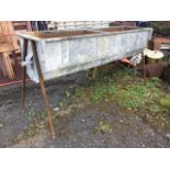 A shaped rectangular galvanised trough with platform rim, raised on stand with angled legs. (74in)