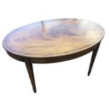 An oval mahogany coffee table inlaid with ebony stringing, raised on angled square tapering legs. (