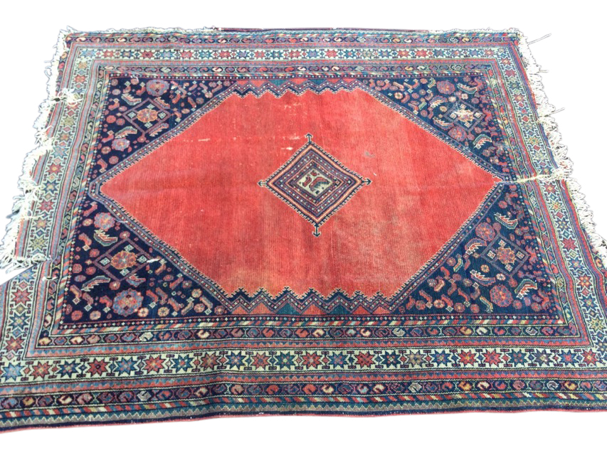 A Bokhara rug woven with central diamond shaped medallion on an orange field framed by ink blue