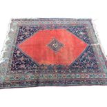 A Bokhara rug woven with central diamond shaped medallion on an orange field framed by ink blue