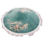 A circular thick-pile Chinese rug woven with flowers on green ground within a fringed border. (