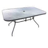 A garden table with rectangular rounded glass top on tubular supports with shaped legs. (56in x 36in