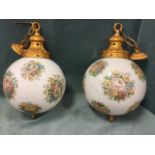 A pair of hanging glass globe lights with floral decoration having gilded mounts, supported on