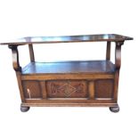 An oak monks bench with cleated back/top on shaped arm supports above a panelled coffer with