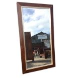 A large rectangular mirror with bevelled plate in silvered border, within a wide stained angled