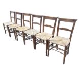 A set of six elm chairs with shaped platform back rails above rush seats, raised on turned legs &