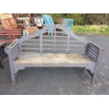 A Lutyens style garden bench with scalloped arched lattice back above a rectangular slatted seat,