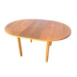 An extending oak dining table, the circular top with integral flip-over leaf, raised on rounded