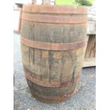 An oak whiskey barrel, the staves bound by six riveted metal strap bands. (34.5in)