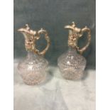 A pair of cut glass claret jugs with scrolled silver plated mounts embossed with flowers having