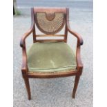 A regency style mahogany armchair with crescent shaped caned back and scrolled arms above a cane