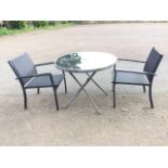 A circular glass-top garden table and pair of armchairs, the folding table on tubular legs, the