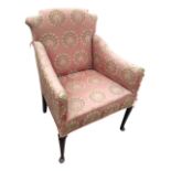 An Edwardian upholstered armchair with shaped back and downswept arms above a sprung seat, raised on