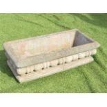 A rectangular composition stone garden trough with cushion moulded rim above a lobbed frieze, raised