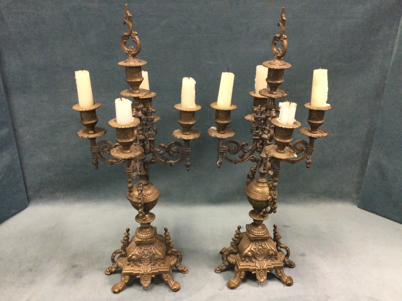 A pair of brass candelabra each with four scrolled branches on decorative urn columns with