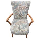 A beech armchair with waisted padded back above rounded arms and sprung cushion seat, raised on
