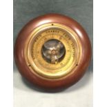 An English made circular aneroid barometer in mahogany cushion moulded case, with brass dial under