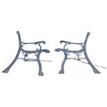 A pair of cast iron bench ends with scrolled decoration to channelled frames, raised on sabre legs -