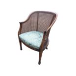 A mahogany bergére armchair with rounded back and scrolled arms above a drop-in upholstered seat,