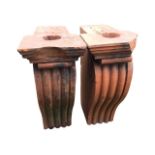 A pair of terracotta architectural corbels with fluted scrolls beneath moulded platforms. (23in x