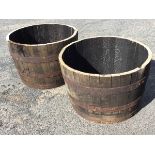 A pair of oak barrel planters, the tubs with staves each bound by three riveted metal strap