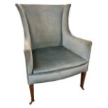 An Edwardian mahogany upholstered wing armchair with waisted back above a sprung upholstered seat,