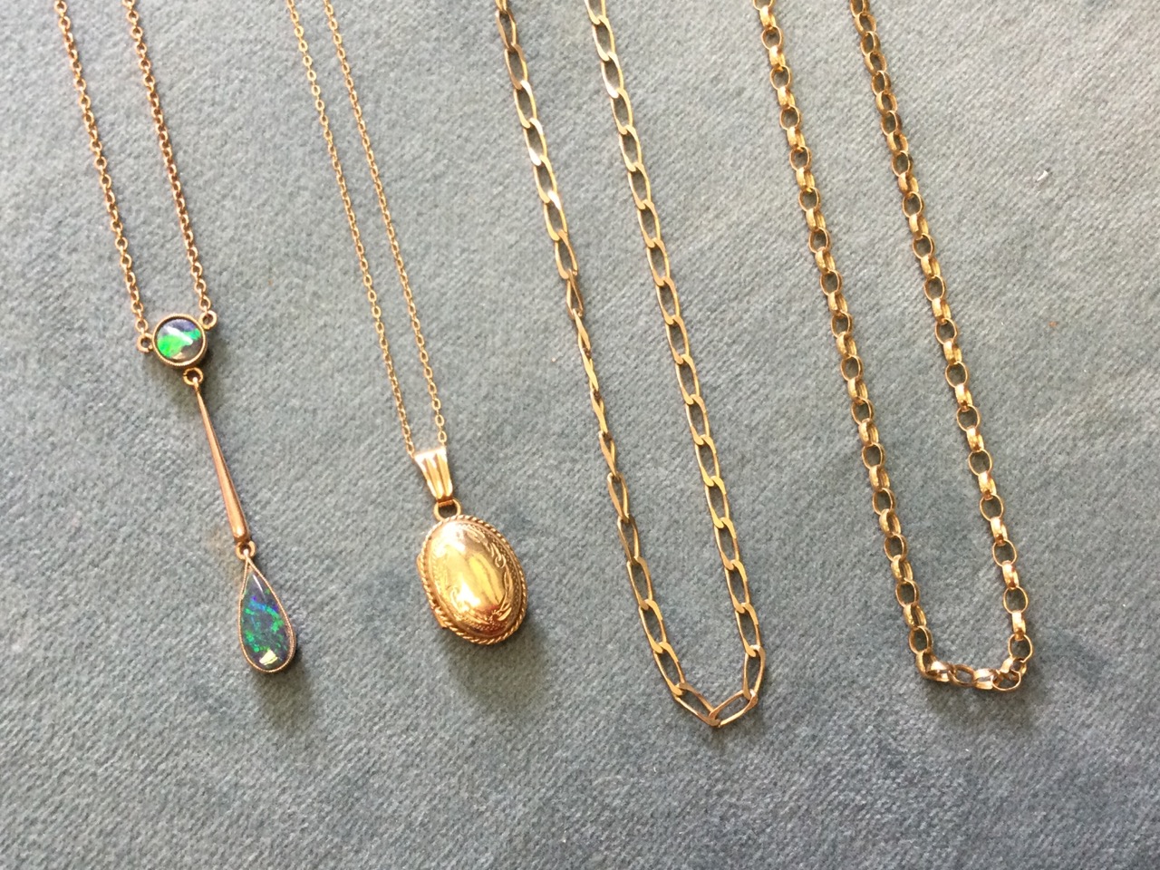 A 9ct gold mounted opal pendant on chain; a small oval 9ct gold locket on fine chain; and two long