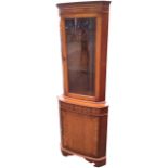 A reproduction bowfonted yew corner cabinet with dentil cornice above glazed door with cut