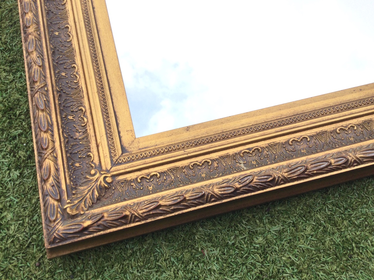 A rectangular gilt framed mirror, the frame with leaf and scroll embossed decoration. (44.75in x - Bild 2 aus 3