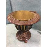 A mahogany wine cooler with brass bucket in slatted basket cage beneath a flat ribbed rim, raised on
