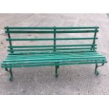 A slatted and painted garden bench raised on three wrought iron scrolled supports. (70in)