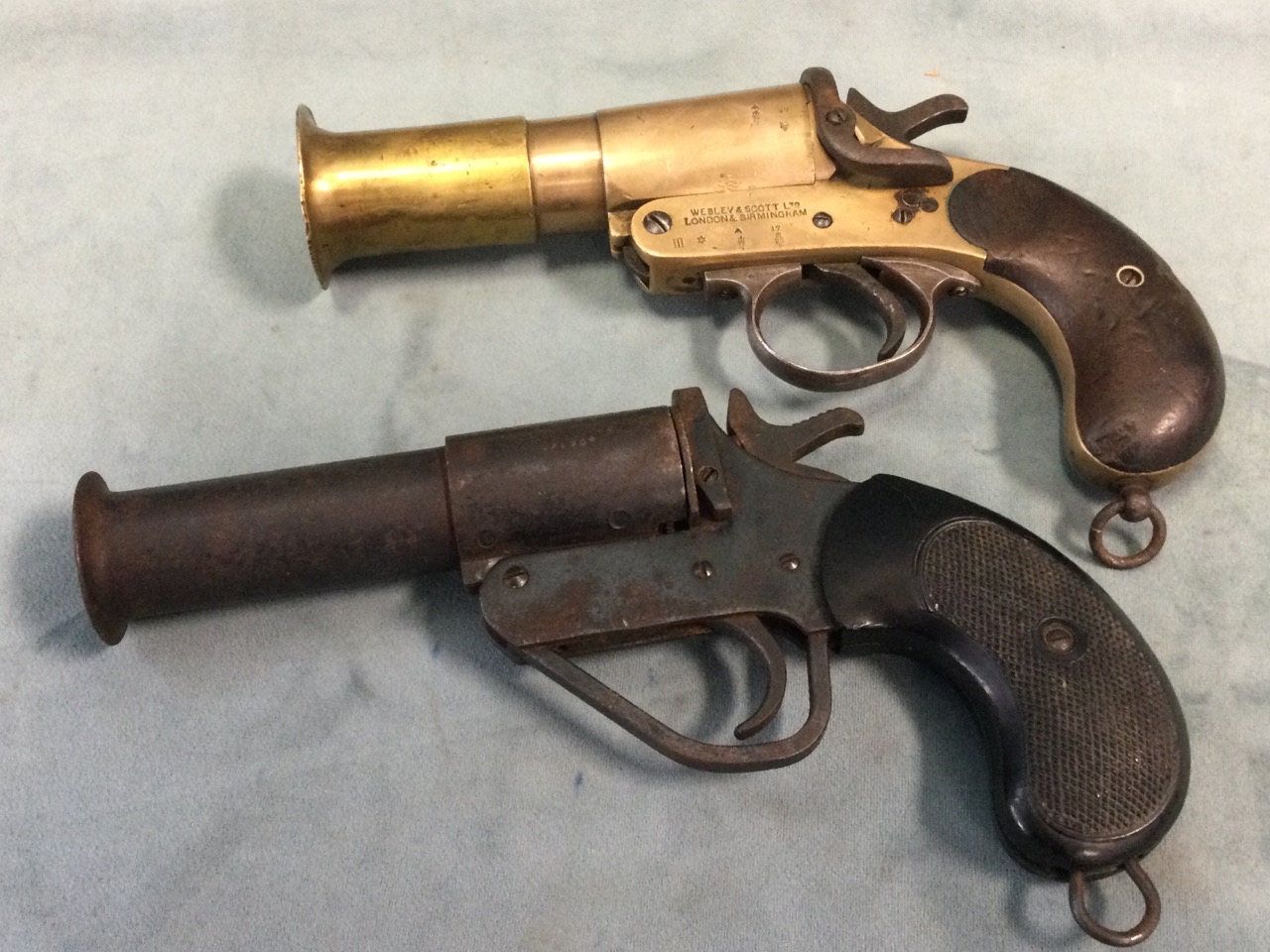An Edwardian brass Webley & Scott 1in flare pistol with mahogany handle; and another similar in