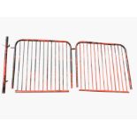 A pair of large painted tubular metal gates with vertical bars in rounded frames, together with a