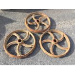 A set of three cast iron wheels with central hubs and flat 3in rims, each with five crescent