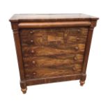 A Victorian mahogany chest of drawers framed by turned columns, having column mounted frieze