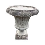 A composition stone urn with overhanging lobbed rim above a body cast with ribbed shell panels,