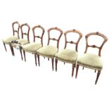 A set of six Victorian walnut dining chairs, the backs carved with roundels and scrolls, having