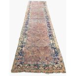 An Anatolian runner woven with floral madder field with linked foliage framed by ink blue frieze