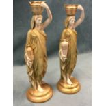A pair of Royal Worcester water carrier figurines, each classically draped figure holding a