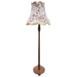 A mahogany standard lamp with floral fringed shade, the tapering turned column on circular moulded