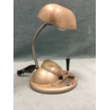A 1950s desk tablelamp with adjustable light above a circular base with electric clock, ashtray,