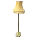 A brass standard lamp with plain column on circular weighted base, mounted with fabric tasseled