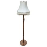 A hardwood standard lamp with octagonal fringed fabric shade on fluted turned column above a