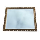 A contemporary rectangular gilt framed mirror with bevelled plate in pierced gilt scrolled frame. (
