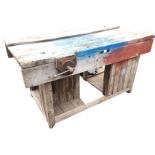 An old hardwood workbench with rectangular channelled top mounted with cast iron vice, raised on