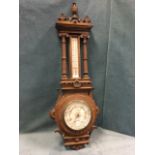 A Victorian oak barometer, the carved case surmounted by an urn finial above a dentil cornice and