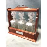 A reproduction mahogany tantalus with silver plated mounts, the three square-cut decanters with ball