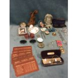 A tin of miscellaneous collectors items including a doll, a pair of gilt enamelled cranberry